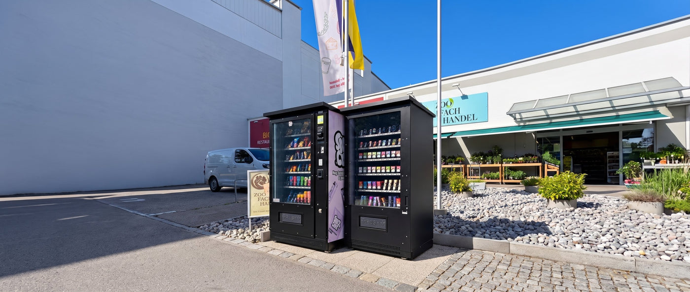 Zwei Automaten vor einem Geschäft mit Parkplatz
